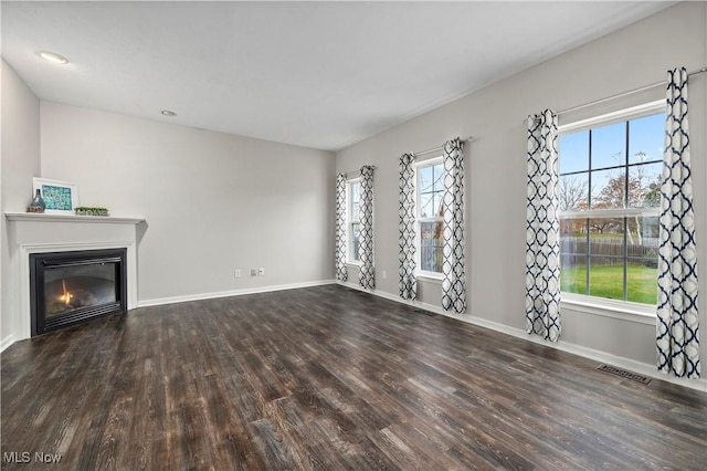 unfurnished living room with a wealth of natural light and dark wood-type flooring