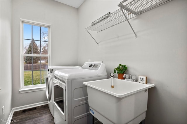 laundry room featuring washer and clothes dryer, dark hardwood / wood-style floors, plenty of natural light, and sink