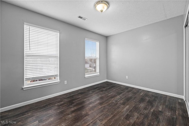 spare room featuring a textured ceiling and dark hardwood / wood-style flooring