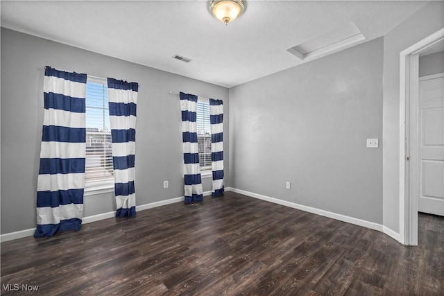 spare room featuring dark hardwood / wood-style flooring and a healthy amount of sunlight