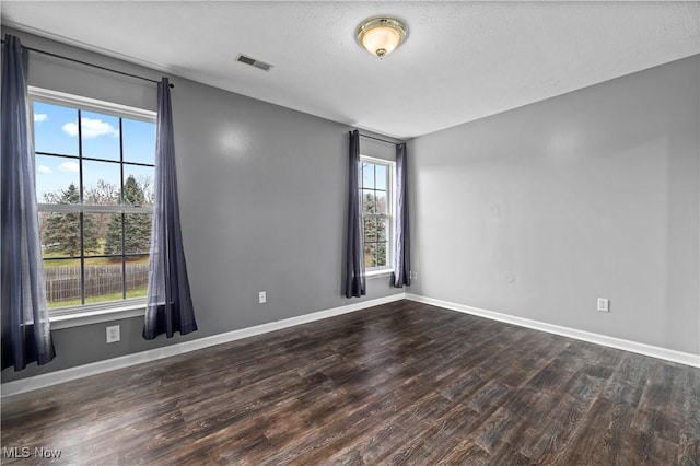 empty room featuring dark hardwood / wood-style floors and a textured ceiling