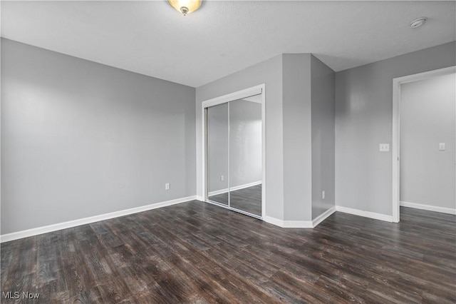 unfurnished bedroom with dark hardwood / wood-style flooring and a closet