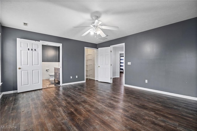 unfurnished bedroom featuring connected bathroom, ceiling fan, dark hardwood / wood-style flooring, and a textured ceiling