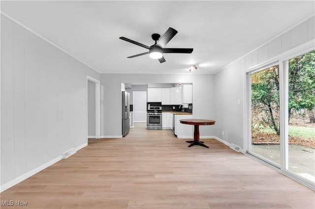 kitchen with white cabinets, sink, light hardwood / wood-style flooring, ornamental molding, and stainless steel appliances