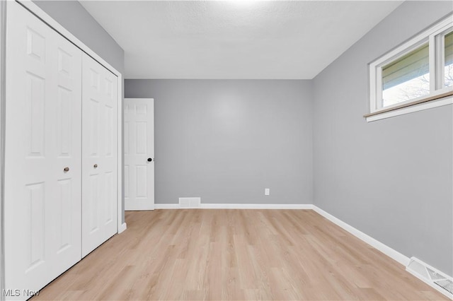 unfurnished bedroom with a closet, a textured ceiling, and light hardwood / wood-style flooring