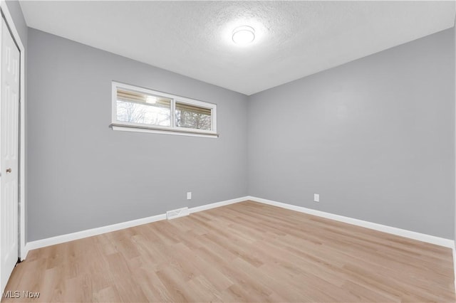 interior space featuring light wood-type flooring and a textured ceiling