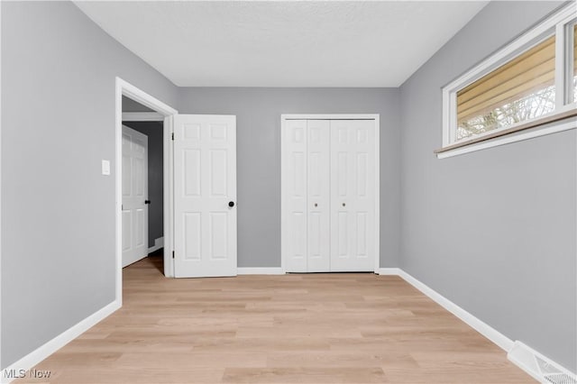 unfurnished bedroom featuring a closet and light hardwood / wood-style floors