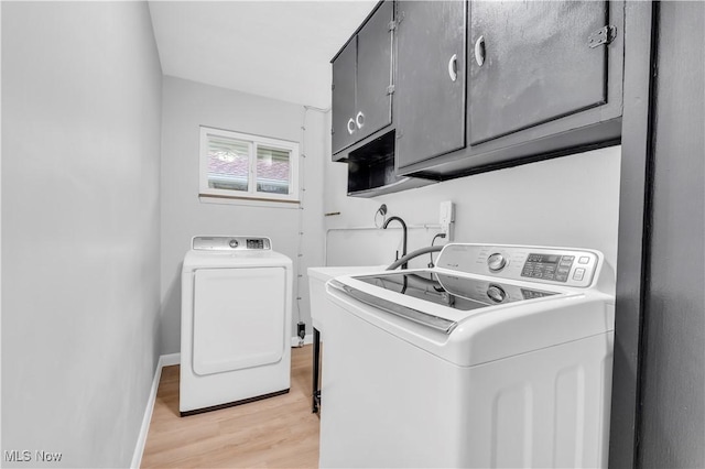 laundry area featuring washer and clothes dryer, cabinets, and light hardwood / wood-style floors