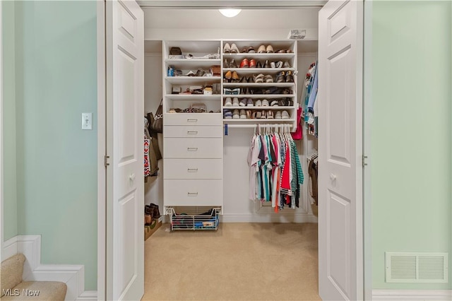 walk in closet with light carpet