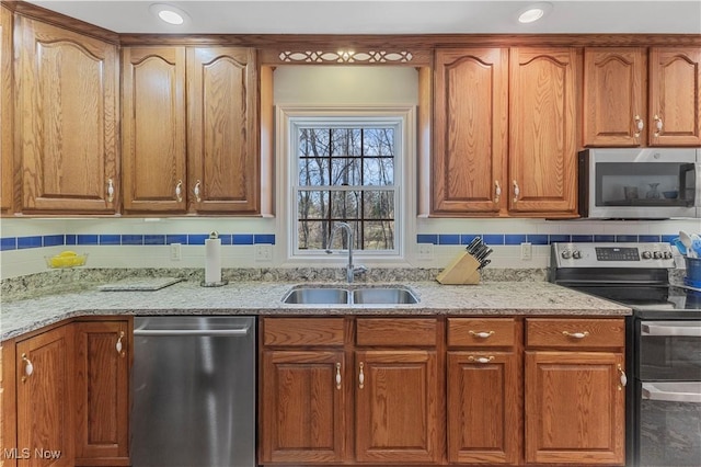 kitchen with light stone countertops, appliances with stainless steel finishes, decorative backsplash, and sink