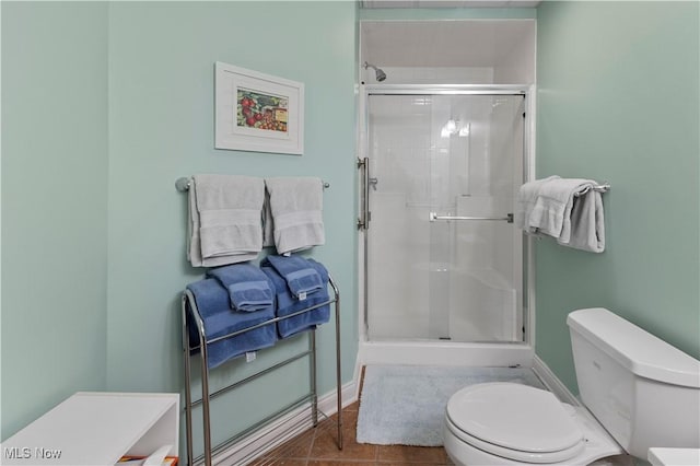 bathroom with tile patterned floors, a shower with shower door, and toilet