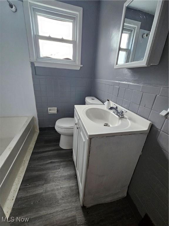 bathroom featuring vanity, hardwood / wood-style flooring, toilet, and tile walls