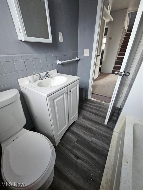 bathroom with hardwood / wood-style flooring, vanity, toilet, and tile walls