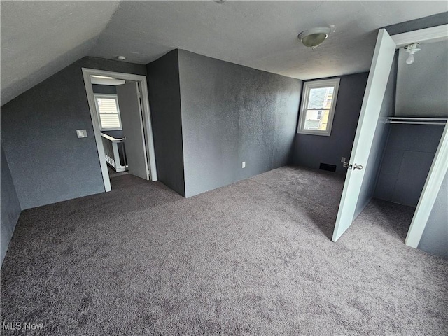 bonus room featuring a textured ceiling, carpet floors, and lofted ceiling