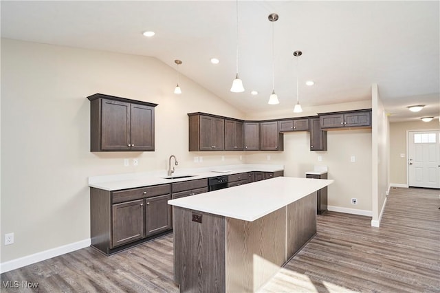 kitchen featuring vaulted ceiling, sink, light hardwood / wood-style flooring, a kitchen island, and hanging light fixtures