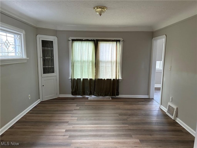 empty room featuring a textured ceiling and dark wood-type flooring