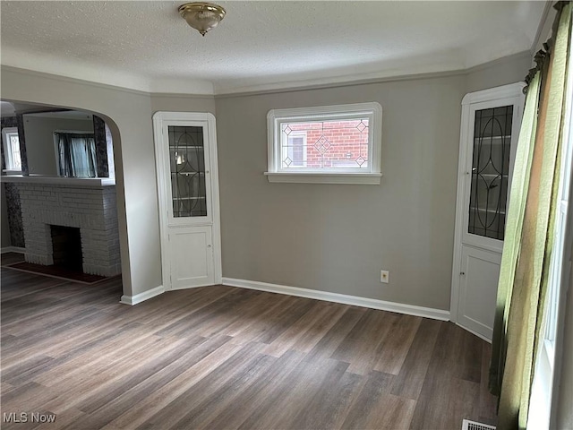 spare room with a fireplace, a textured ceiling, and dark hardwood / wood-style flooring