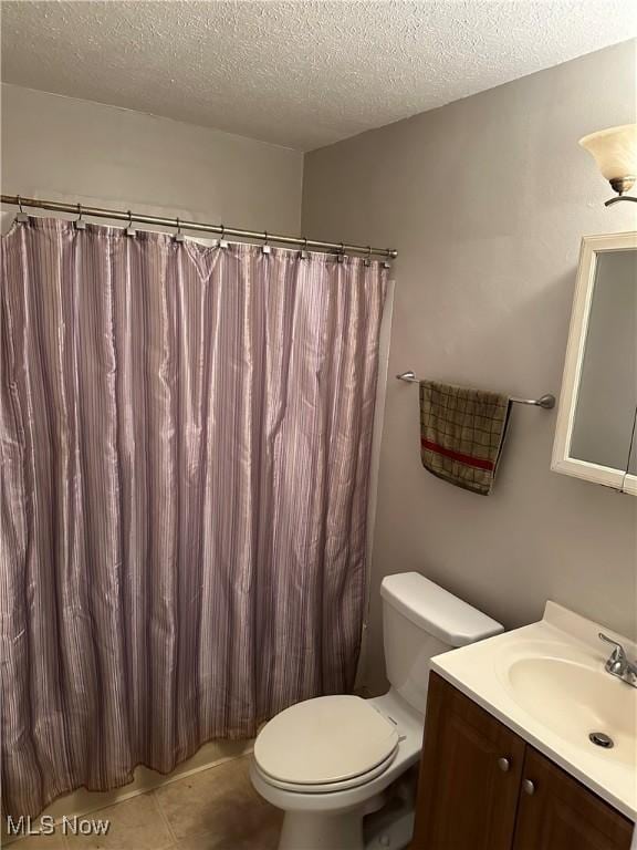 bathroom featuring tile patterned floors, vanity, a textured ceiling, and toilet