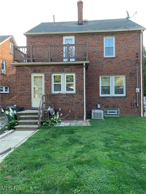 rear view of property featuring a balcony, cooling unit, and a lawn