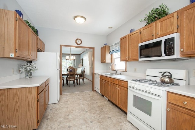 kitchen featuring white appliances, a notable chandelier, and sink