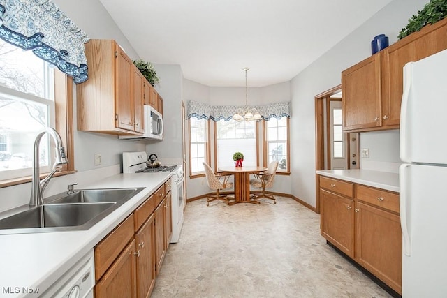 kitchen with a chandelier, white appliances, hanging light fixtures, and sink