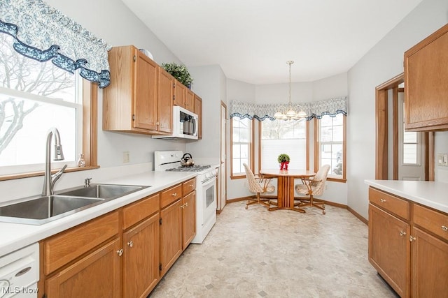 kitchen with sink, white appliances, hanging light fixtures, and a chandelier