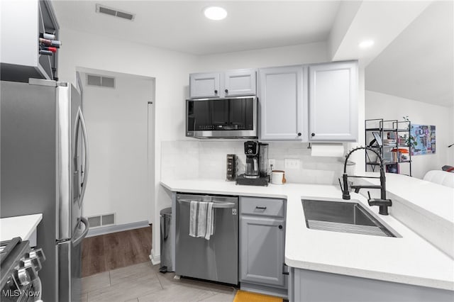 kitchen with decorative backsplash, stainless steel appliances, gray cabinets, and sink