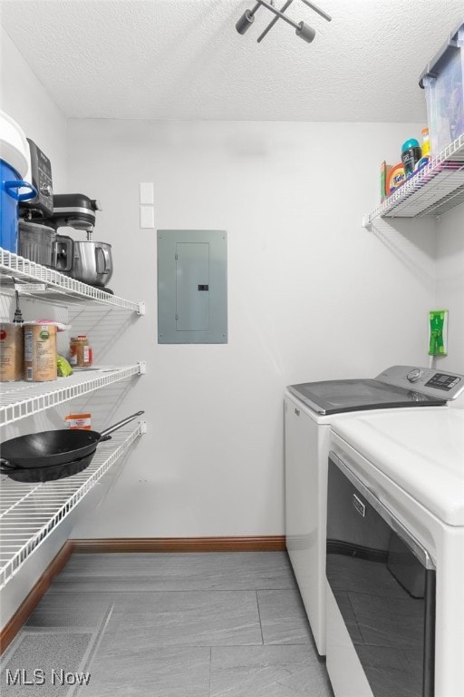 laundry room with washer and dryer, a textured ceiling, and electric panel