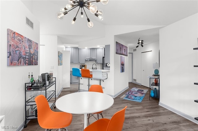 dining area with lofted ceiling, dark hardwood / wood-style floors, a notable chandelier, and sink