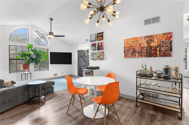 dining space featuring ceiling fan with notable chandelier, hardwood / wood-style flooring, and vaulted ceiling