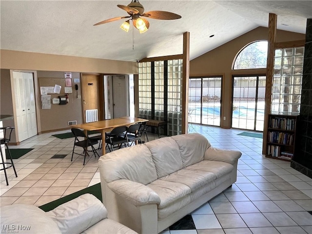 living room with a textured ceiling, ceiling fan, light tile patterned floors, and vaulted ceiling