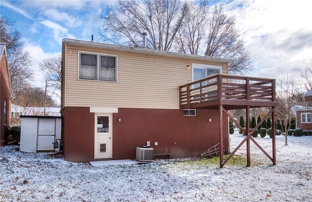 snow covered house with central AC unit and a deck