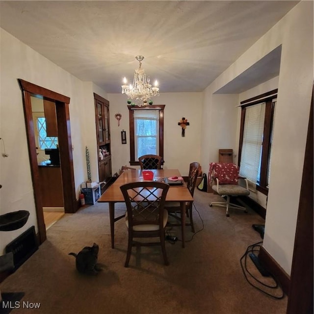 dining area with light carpet and a chandelier