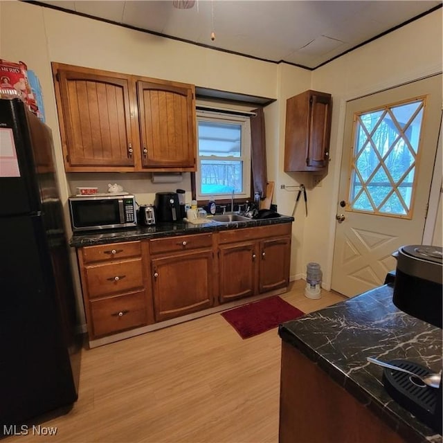 kitchen with black refrigerator, sink, and light hardwood / wood-style flooring