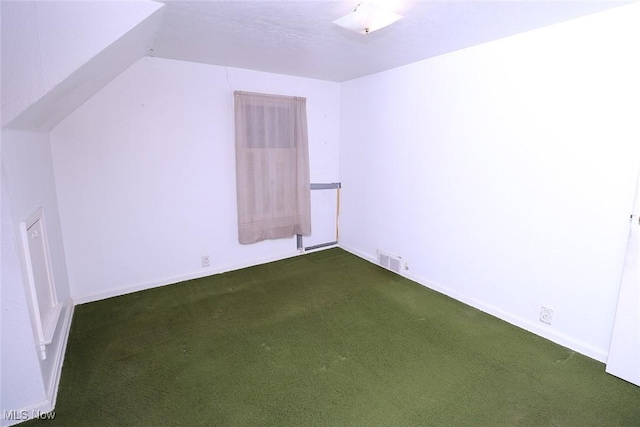 additional living space featuring dark carpet and lofted ceiling