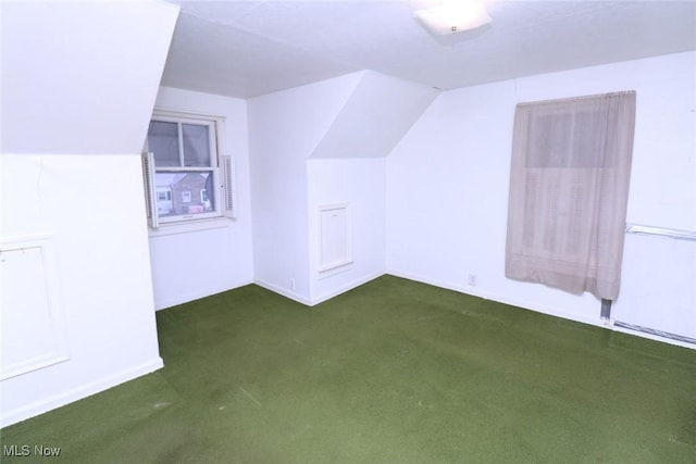 additional living space featuring dark colored carpet and lofted ceiling