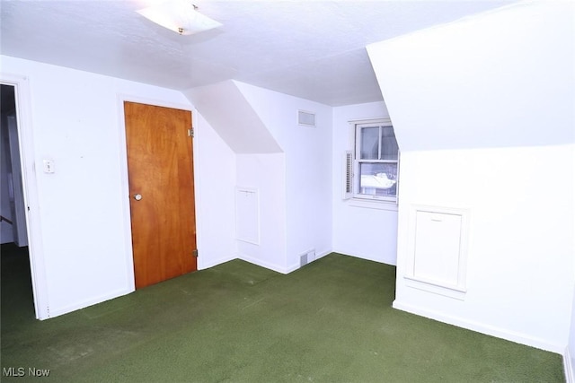 bonus room featuring a textured ceiling, dark carpet, and lofted ceiling