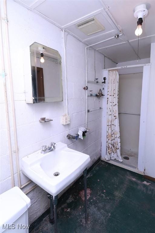 bathroom featuring a shower with shower curtain, toilet, concrete flooring, and sink