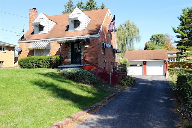 view of front of home with a garage, an outbuilding, and a front lawn