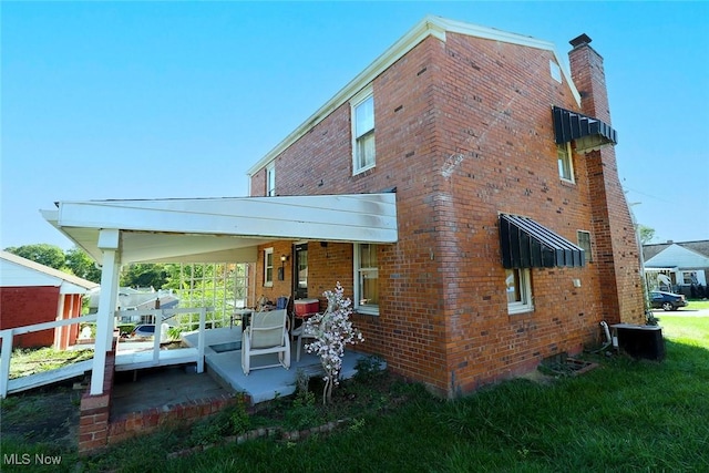 rear view of property featuring a lawn and a patio