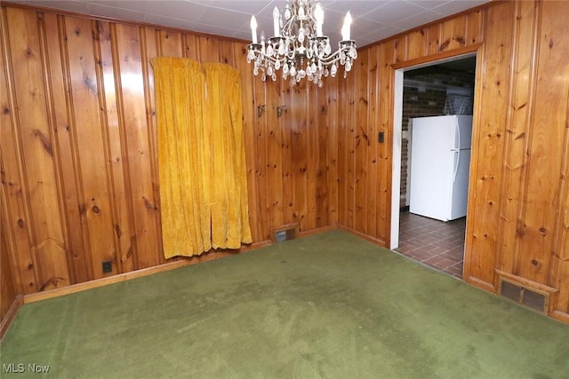 unfurnished room featuring dark colored carpet, a notable chandelier, and wood walls