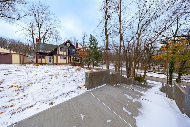 yard layered in snow featuring a garage and an outbuilding