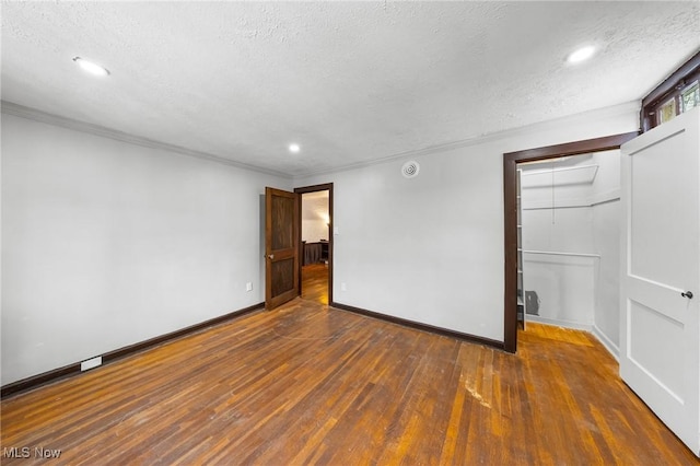 unfurnished room featuring a textured ceiling, crown molding, and dark wood-type flooring