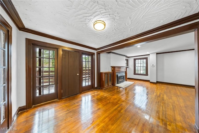 unfurnished living room with hardwood / wood-style floors, a textured ceiling, and ornamental molding