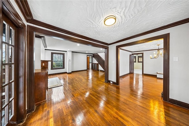 unfurnished living room with a chandelier, hardwood / wood-style flooring, and ornamental molding