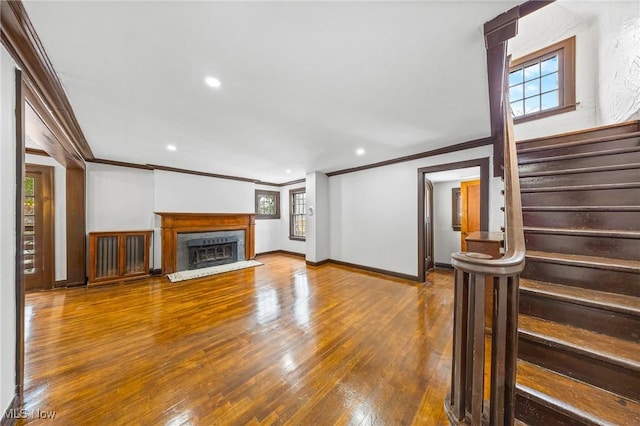 unfurnished living room with hardwood / wood-style floors and crown molding