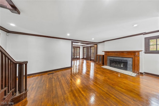 unfurnished living room featuring wood-type flooring, crown molding, and a tiled fireplace