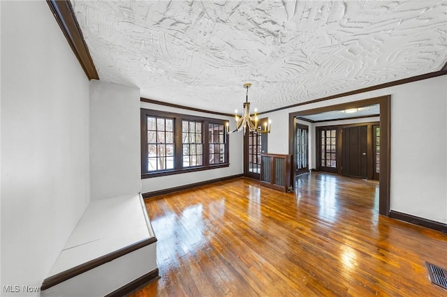 unfurnished dining area featuring crown molding, hardwood / wood-style floors, a chandelier, and a textured ceiling