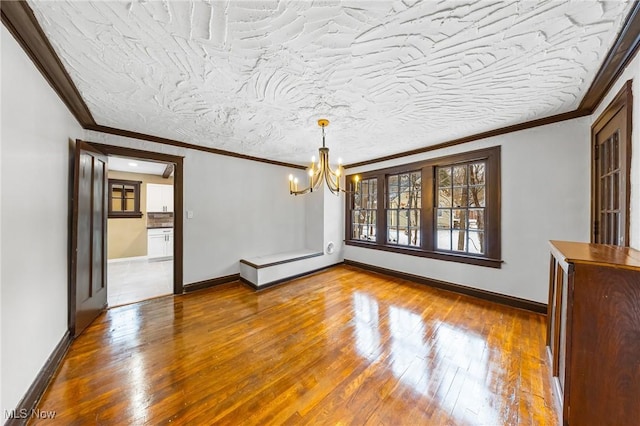 unfurnished dining area featuring hardwood / wood-style floors, a textured ceiling, crown molding, and an inviting chandelier