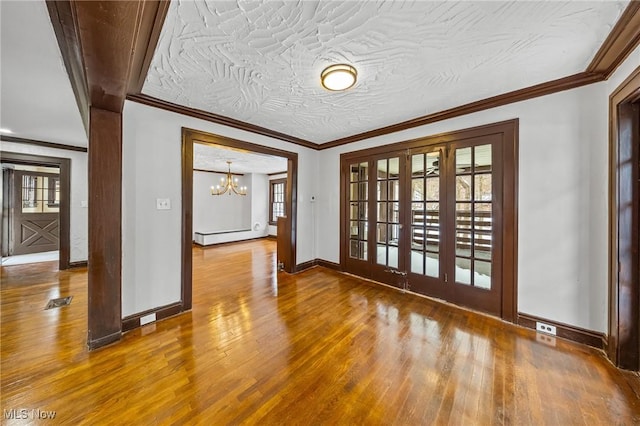 unfurnished room featuring french doors, hardwood / wood-style flooring, an inviting chandelier, and ornamental molding